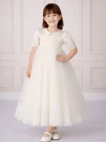 Bambina che indossa un abito da cerimonia lungo in tulle bianco con ricami in pizzo e colletto rotondo.