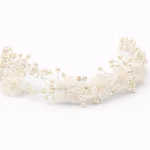 Tralcio gioiello per capelli bambina con perle, cristalli e fiori avorio applicato lateralmente su capelli biondi semiraccolti per cerimonia.