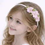 Cerchietto per capelli bambina con bouquet laterale di fiori rosa e dettagli verdi.