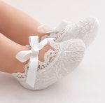 Dettaglio laterale delle scarpette battesimo neonato unisex in pizzo bianco con fiocco elegante