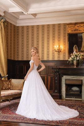 Dettaglio posteriore di un abito da sposa con spalline scese, caratterizzato da schiena scoperta e bottoni decorativi.