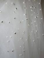 Dettaglio delle perle distribuite sul tulle avorio del velo da sposa