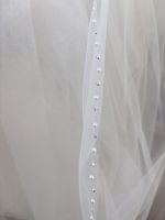 Dettaglio del bordo ondulato con perle e cristalli iridescenti