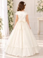 Vista posteriore abito da cerimonia bambina avorio con elegante fiocco in vita, cerniera sul corpetto e gonna lunga vaporosa a strati.