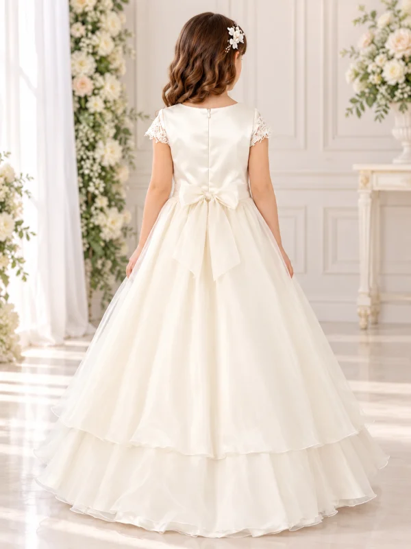 Vista posteriore abito da cerimonia bambina avorio con elegante fiocco in vita, cerniera sul corpetto e gonna lunga vaporosa a strati.