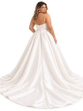 Vista posteriore di abito da sposa curvy principessa in raso avorio, con schiena scoperta, fila di bottoncini rivestiti, ampia gonna strutturata e lungo strascico elegante.