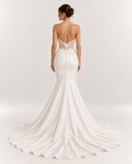 Vista posteriore abito da sposa a sirena avorio con schiena scoperta, corsetto trasparente in pizzo floreale e lunga fila di bottoncini sullo strascico.