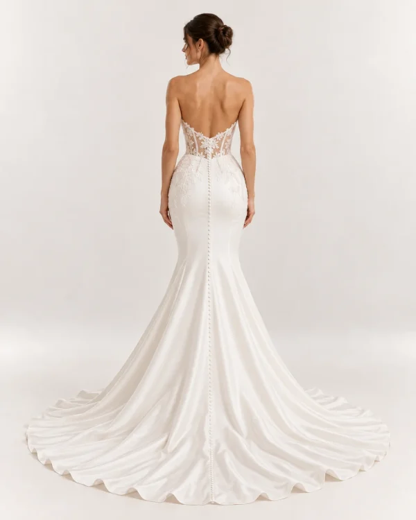 Vista posteriore abito da sposa a sirena avorio con schiena scoperta, corsetto trasparente in pizzo floreale e lunga fila di bottoncini sullo strascico.