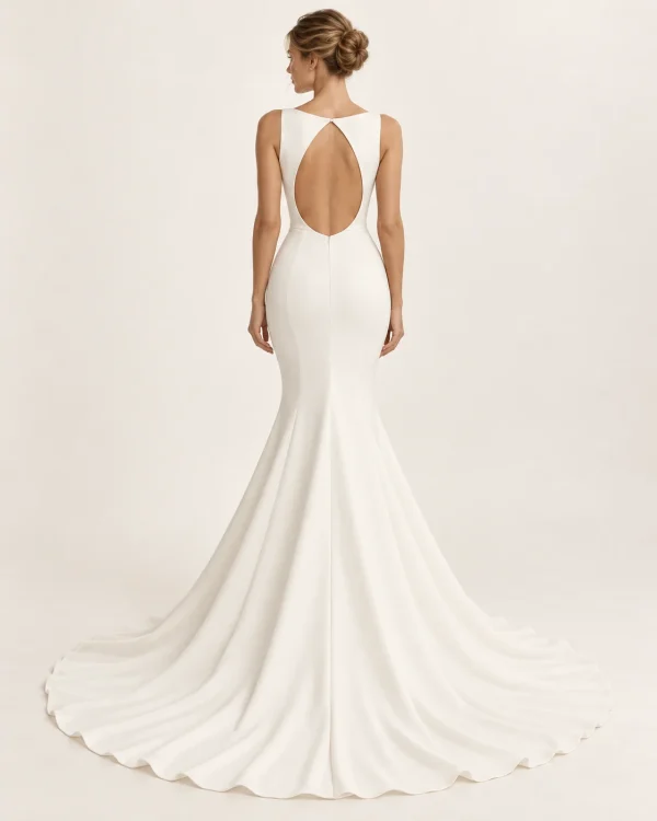 Vista posteriore di abito da sposa a sirena avorio con ampia schiena scoperta a goccia, cuciture sagomate e gonna svasata con lungo strascico.