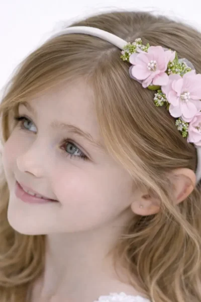 Cerchietto per capelli bambina con bouquet laterale di fiori rosa e dettagli verdi.