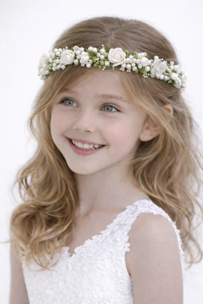 Coroncina gioiello per bambina con fitto intreccio di perle, cristalli e roselline color avorio indossata su capelli biondi mossi per una cerimonia.