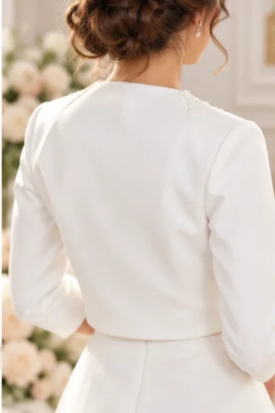 Vista posteriore del bolero coprispalle da sposa bianco corto con maniche tre quarti