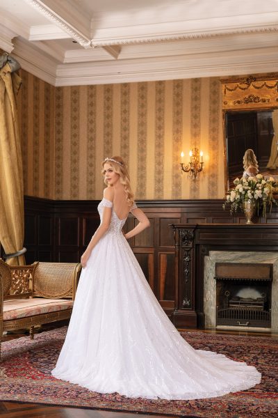 Dettaglio posteriore di un abito da sposa con spalline scese, caratterizzato da schiena scoperta e bottoni decorativi.